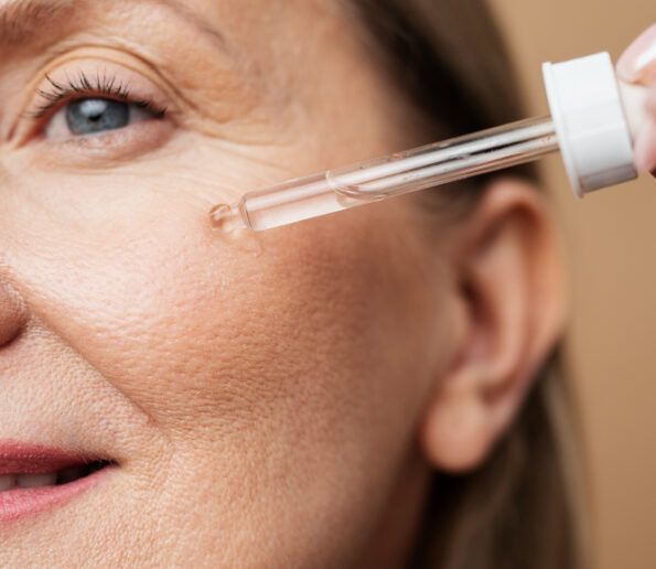 retinol close-up of a woman applying eye serum with a dropper near her eye, focusing on the skin around the eye area.