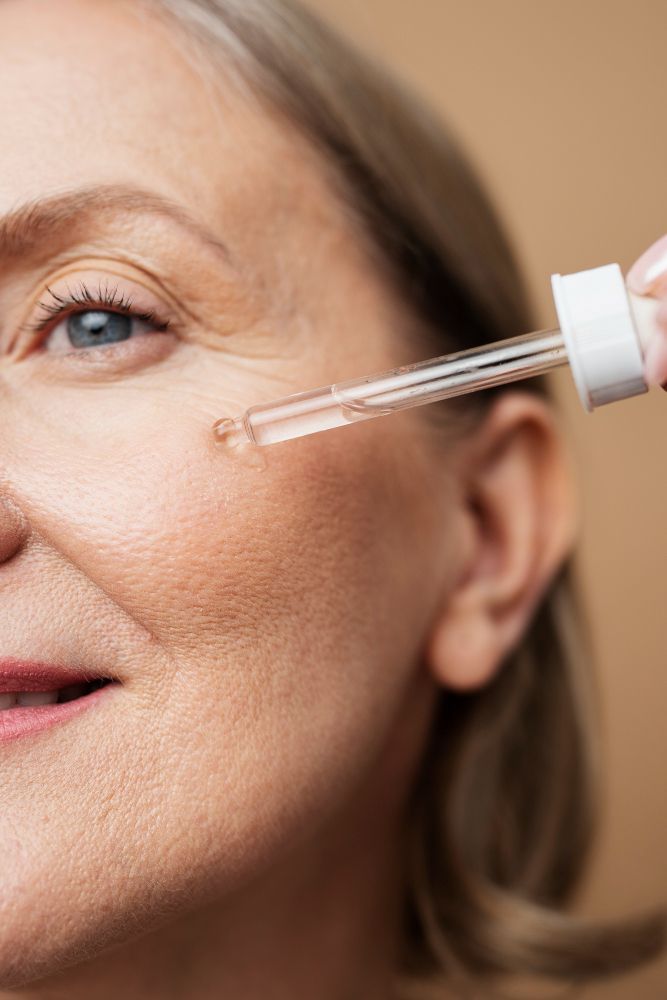 Close-up of a woman applying eye serum with a dropper near her eye, focusing on the skin around the eye area.