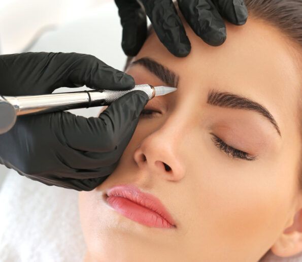 close-up of a beauty professional in black gloves using a pen-like device on a client’s closed eye during a cosmetic eye treatment.