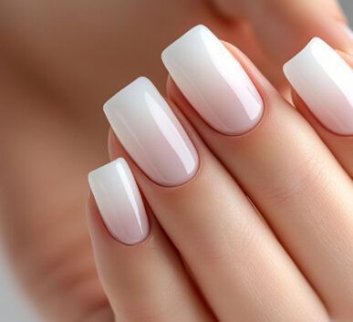 Close-up of a hand showing well-groomed nails with white-to-pale-pink oval tips, glossy finish, and smooth skin.